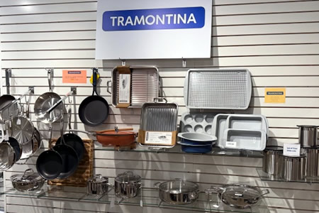 Tramontina cookware display with pots, pans, baking sheets, and kitchen accessories