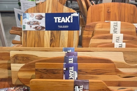 Teak wood cutting boards in assorted sizes and shapes displayed on a store shelf